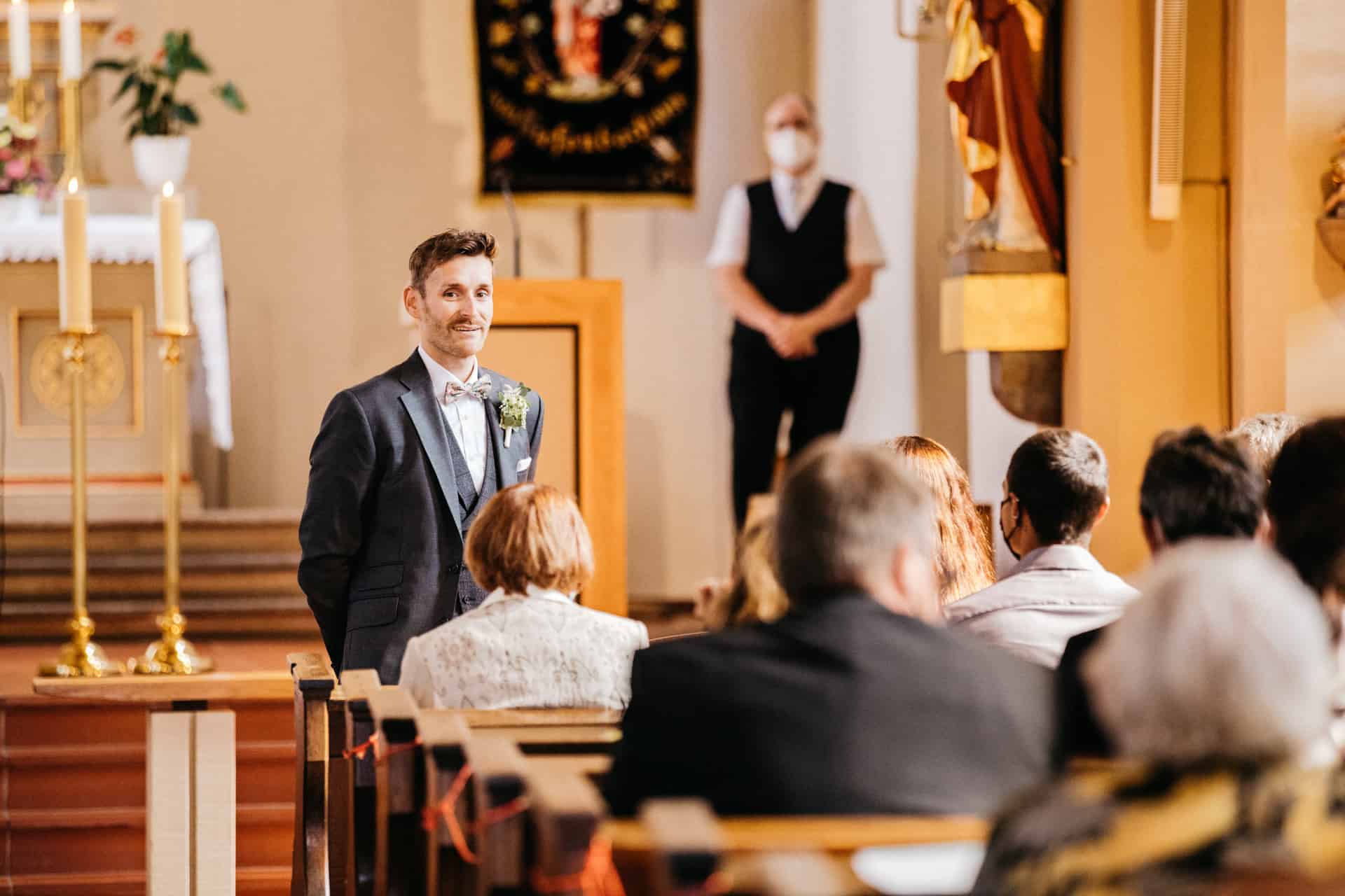 Bräutigam wartet vor den besetzten Kirchenbänken