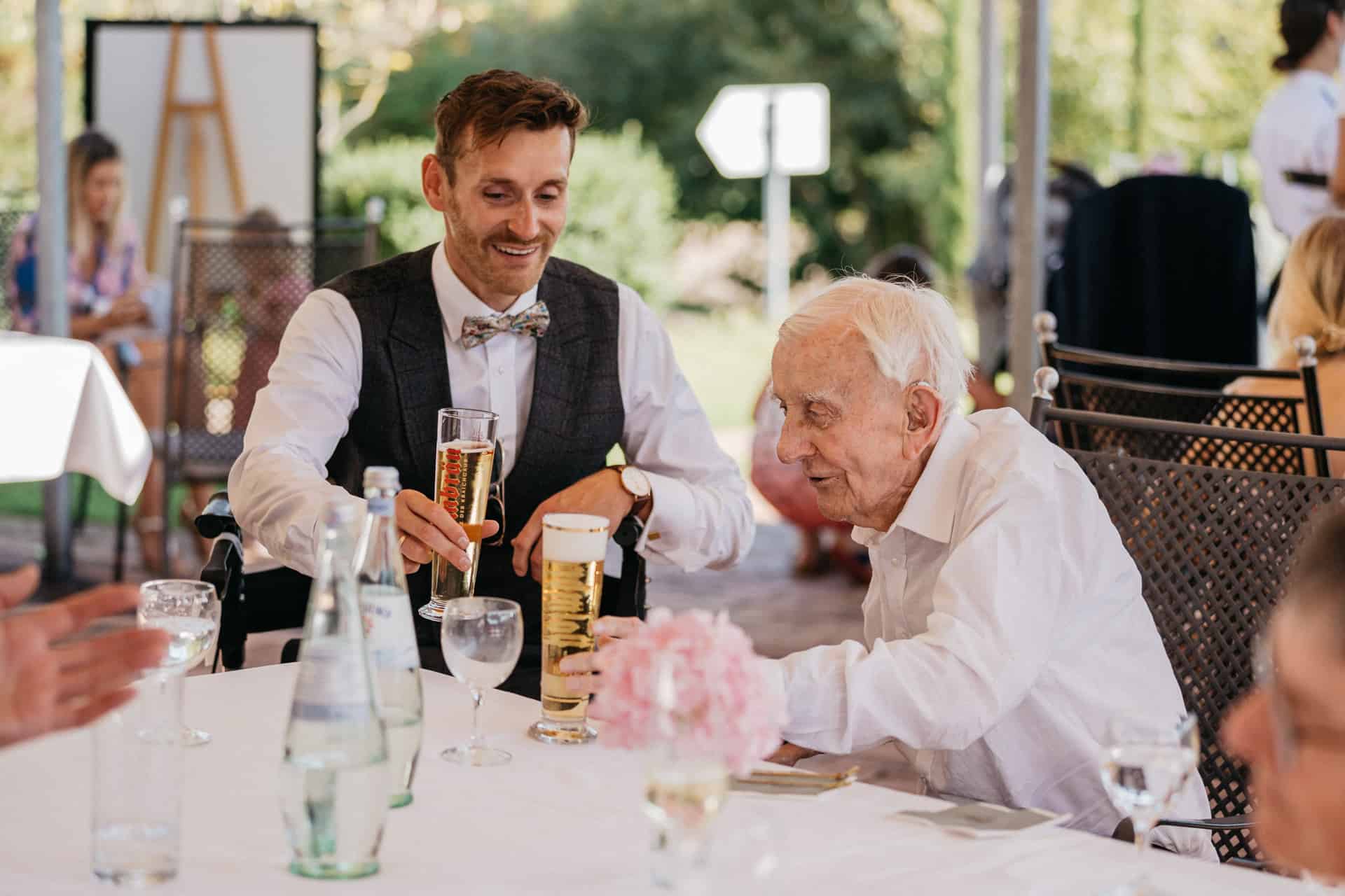 Bräutigam spricht mit einem älteren Gast am Tisch