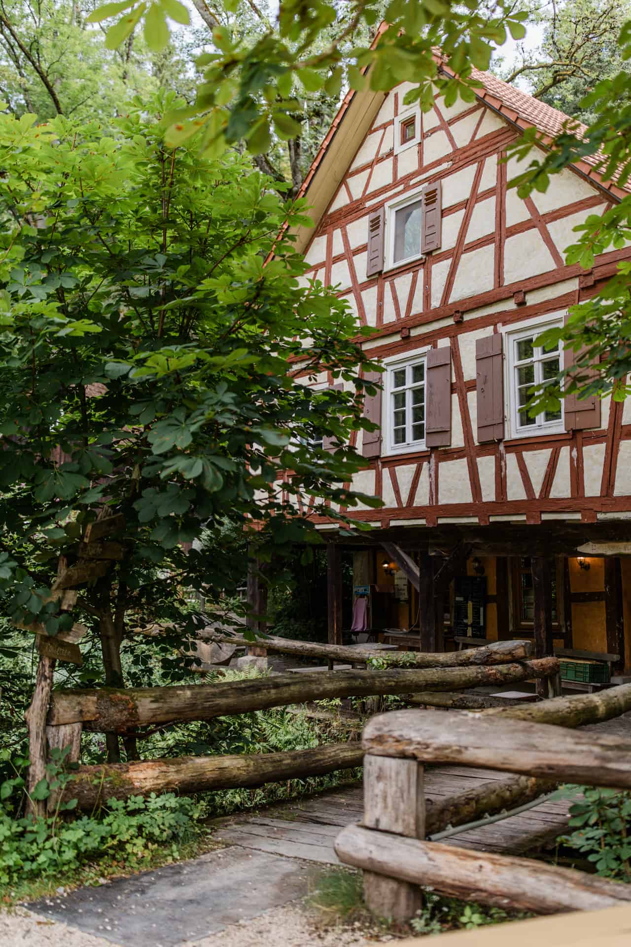 Die Hagmühle in Alfdorf mit Fachwerkfassade und Brücke im Grünen.