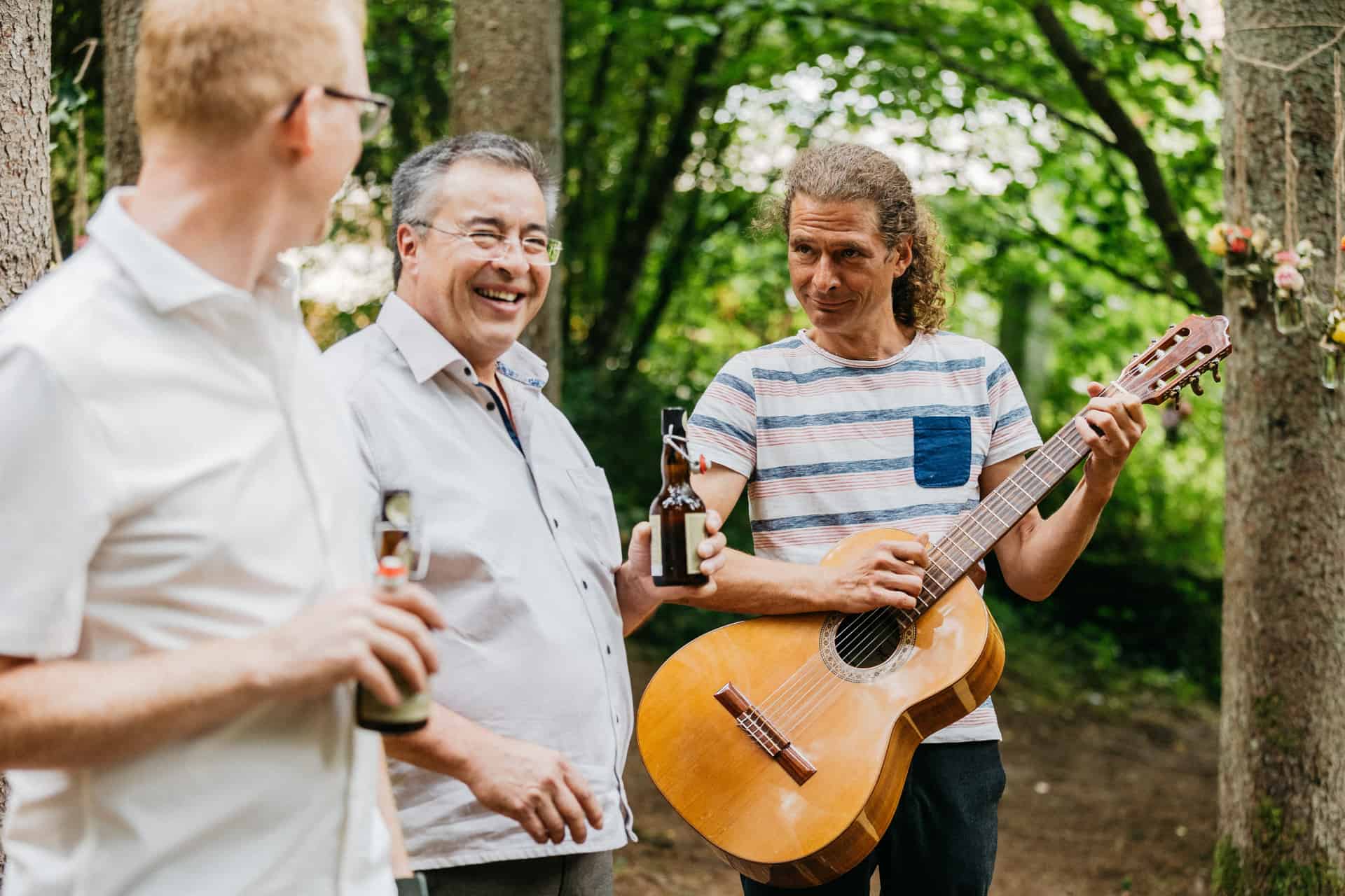 Musiker mit Gitarre am Trauplatz im Wald.