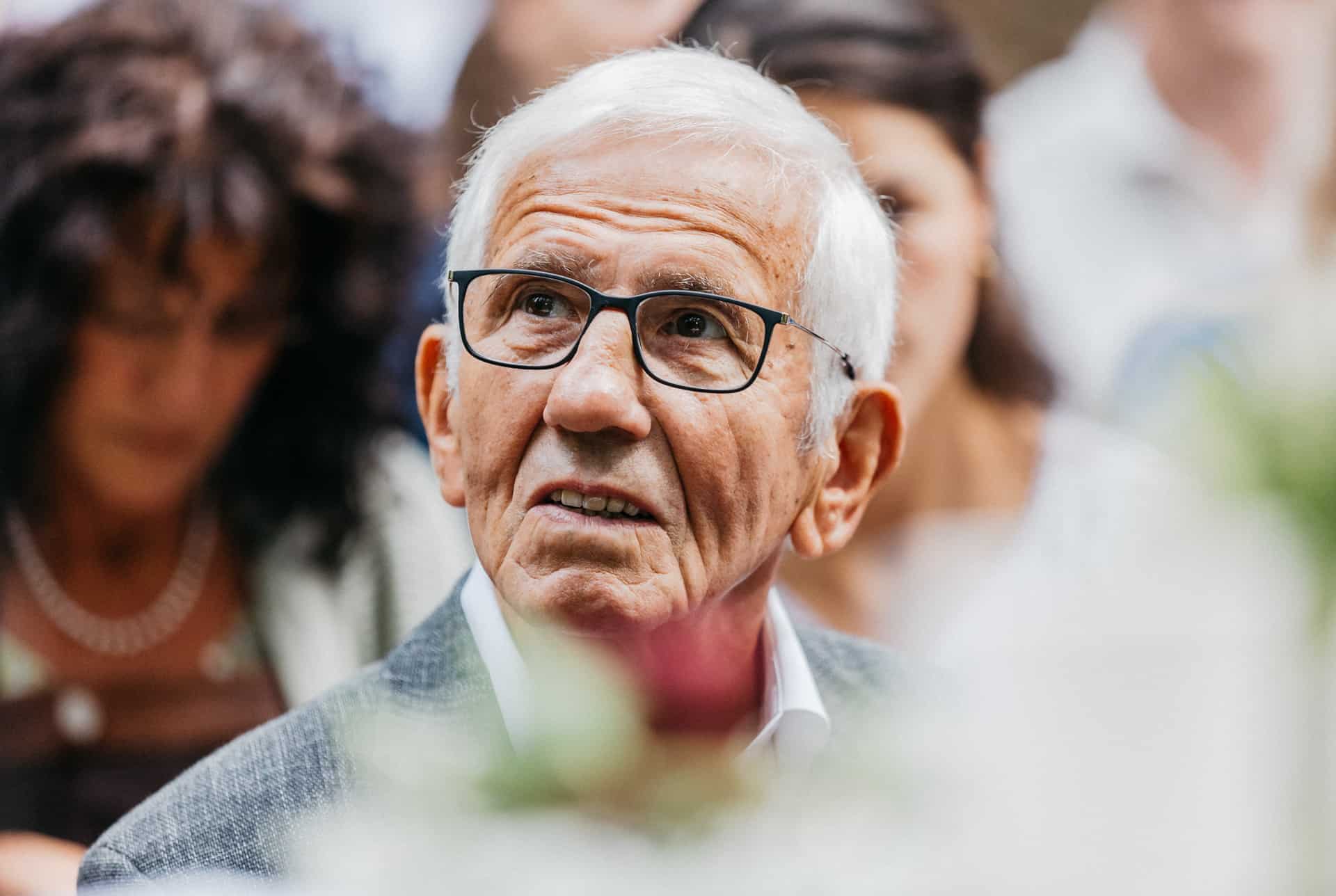Älterer Hochzeitsgast mit Brille während der Zeremonie