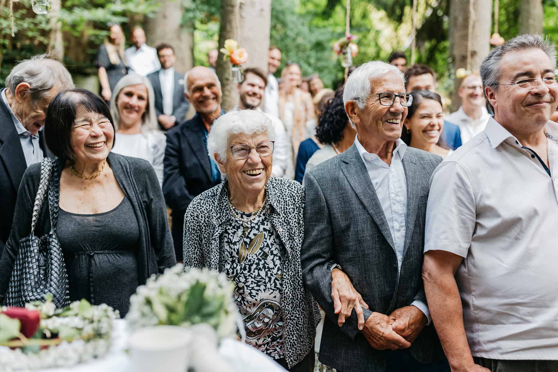 Hochzeitsgäste stehen zum Abschluss der Waldtrauung auf