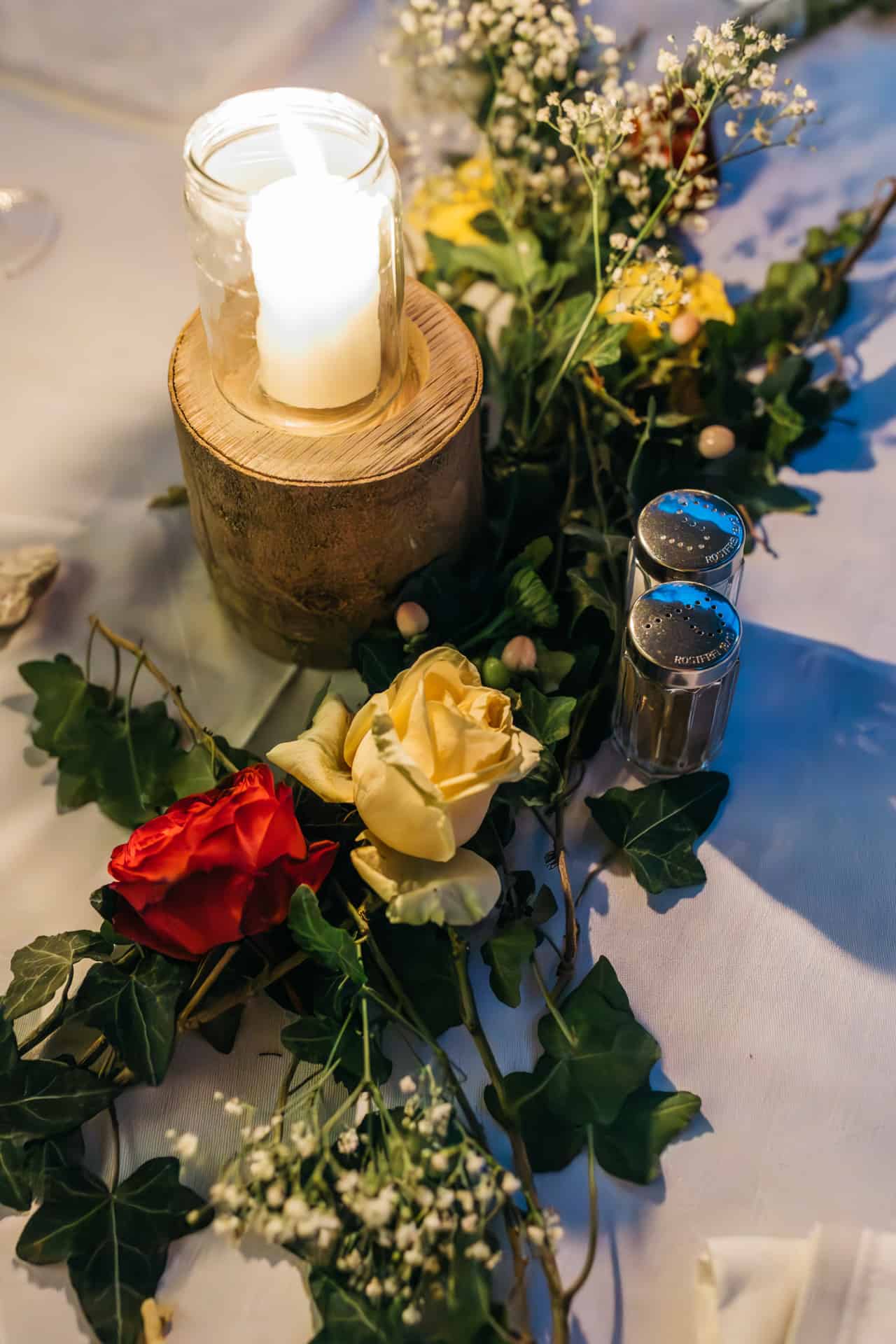 Blumen und Kerze als Tischdekoration bei der Hochzeitsfeier