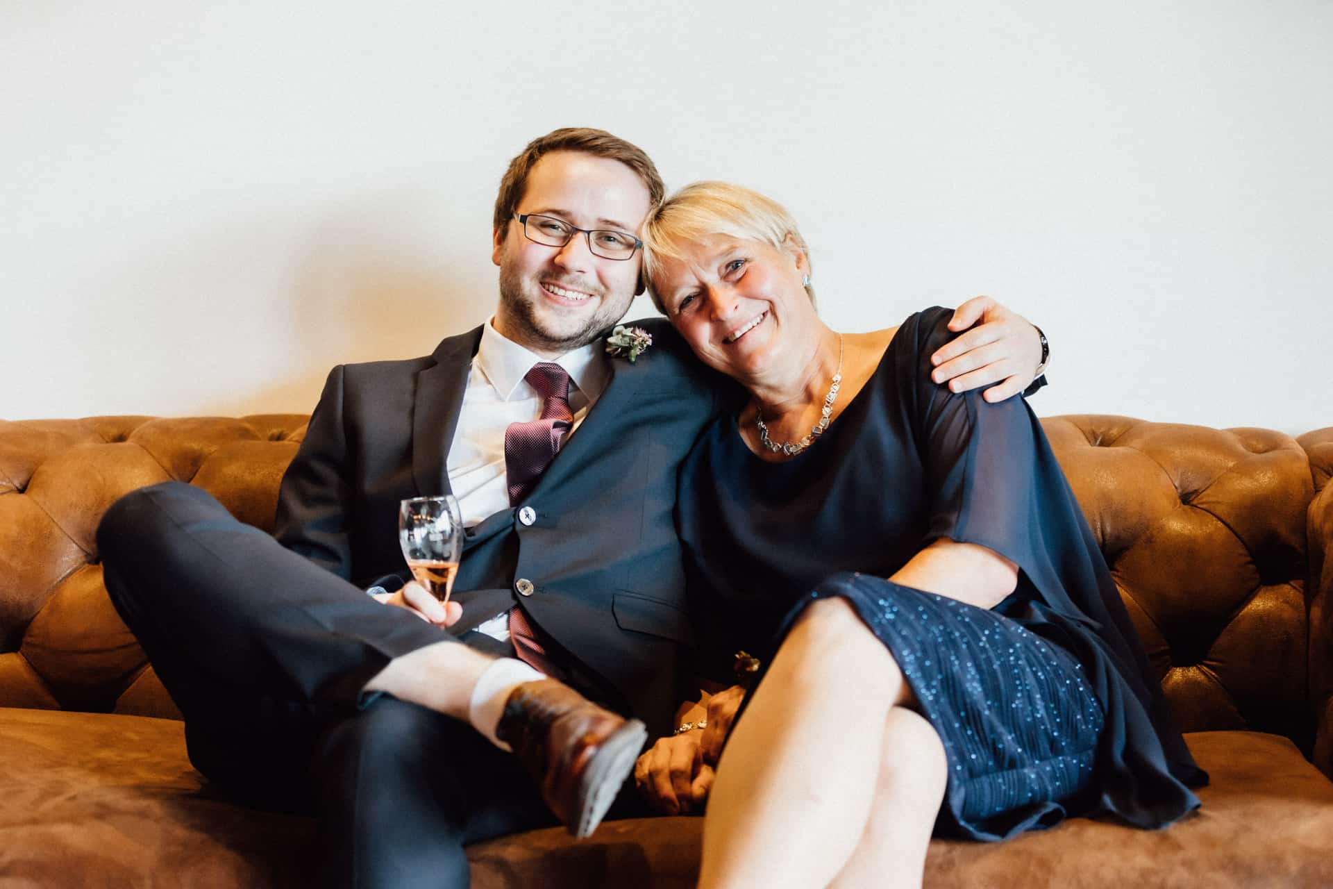 Zwei lachende Gäste sitzen gemeinsam auf einem Sofa