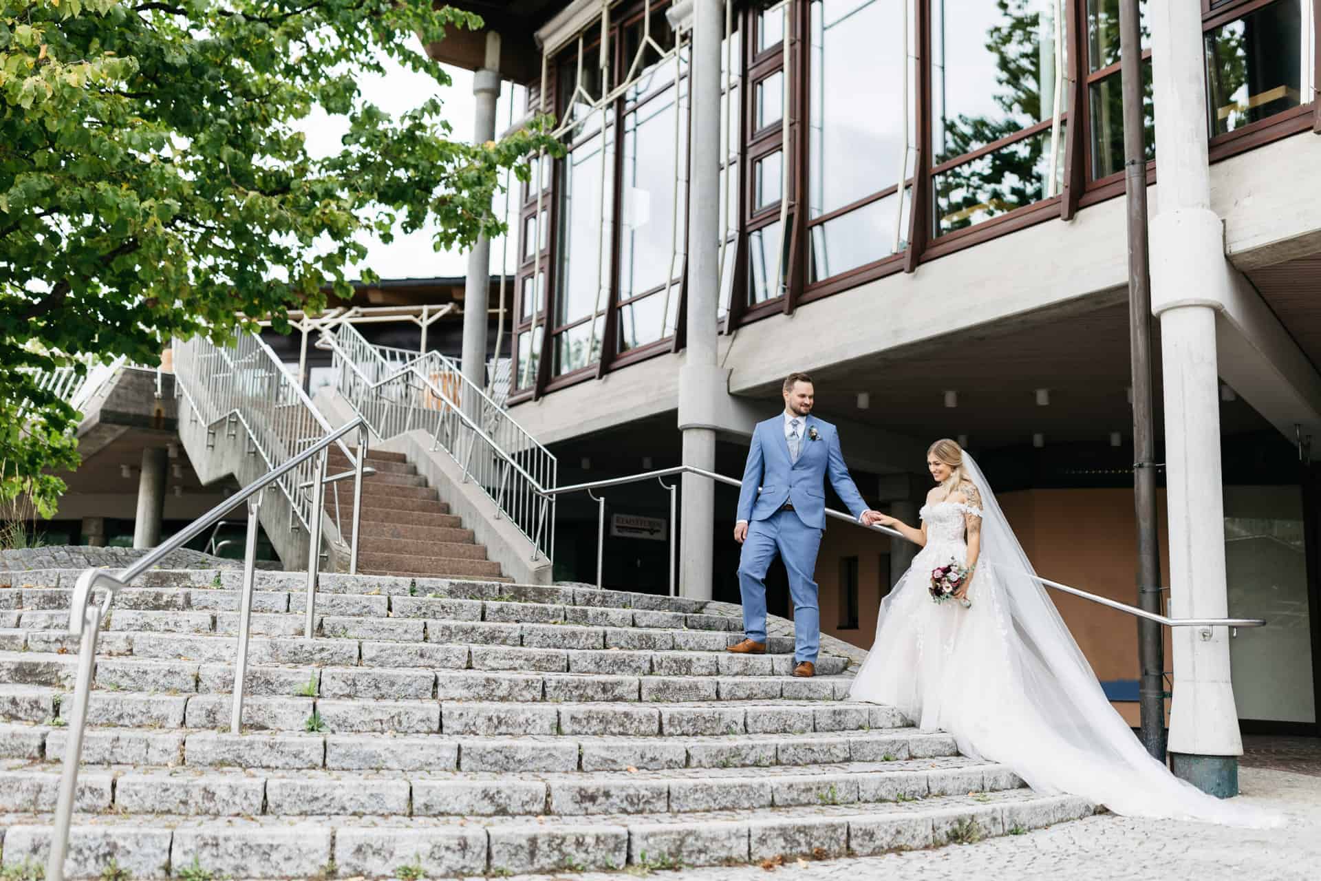 Brautpaar auf einer breiten Treppe vor einem Fachwerkhaus