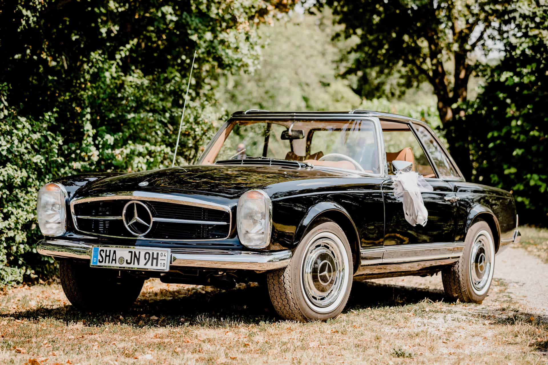 Schwarzer Oldtimer vor grünen Bäumen