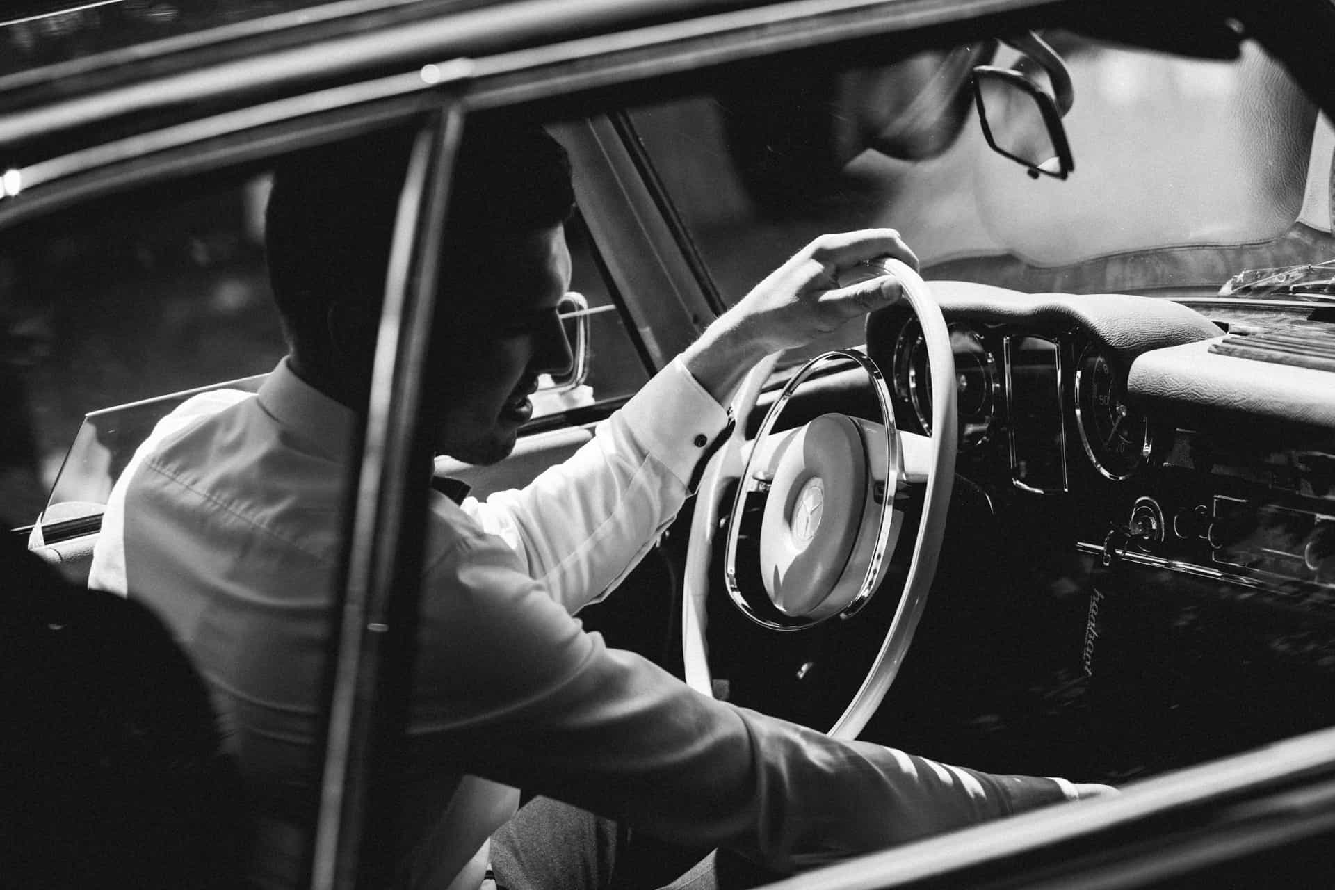 Fahrer im Oldtimer in Schwarz-Weiß