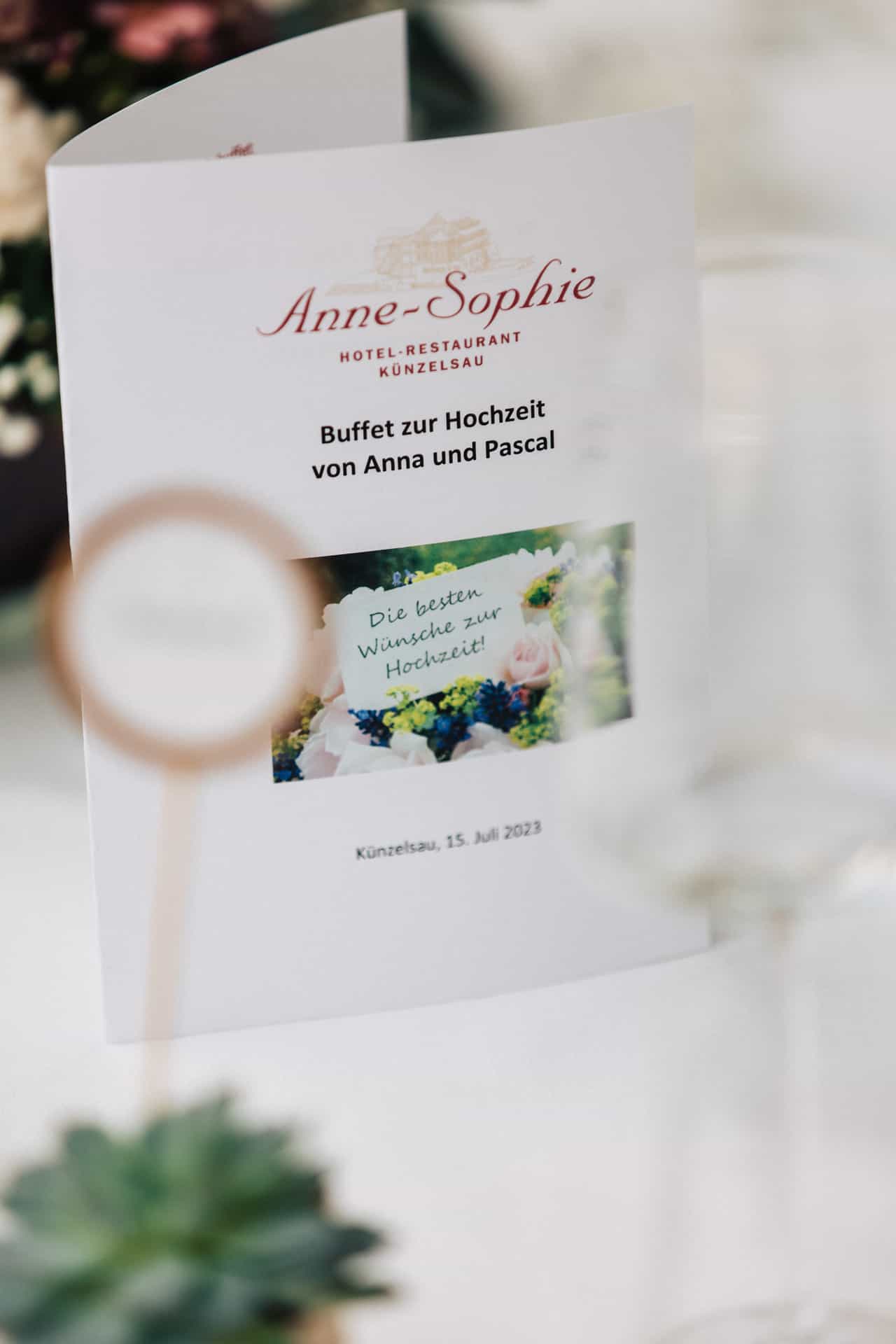 Menükarte zur Hochzeit zwischen Gläsern und Blumen
