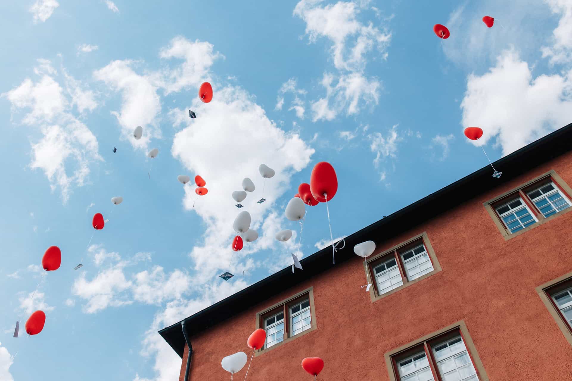 Weiße und orangefarbene Luftballons über den Dächern