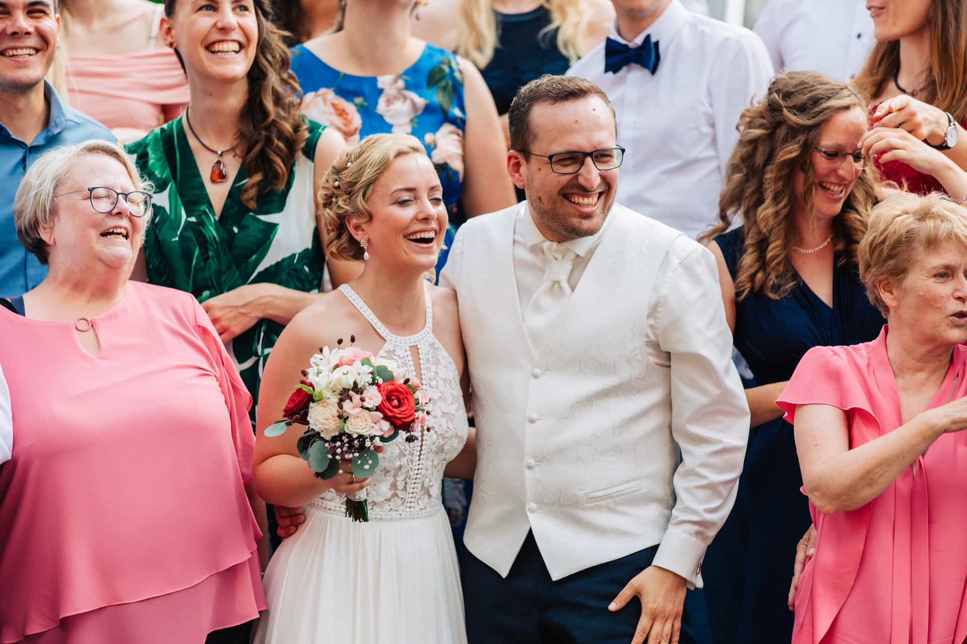 Lachende Gäste beim gemeinsamen Hochzeitsfoto