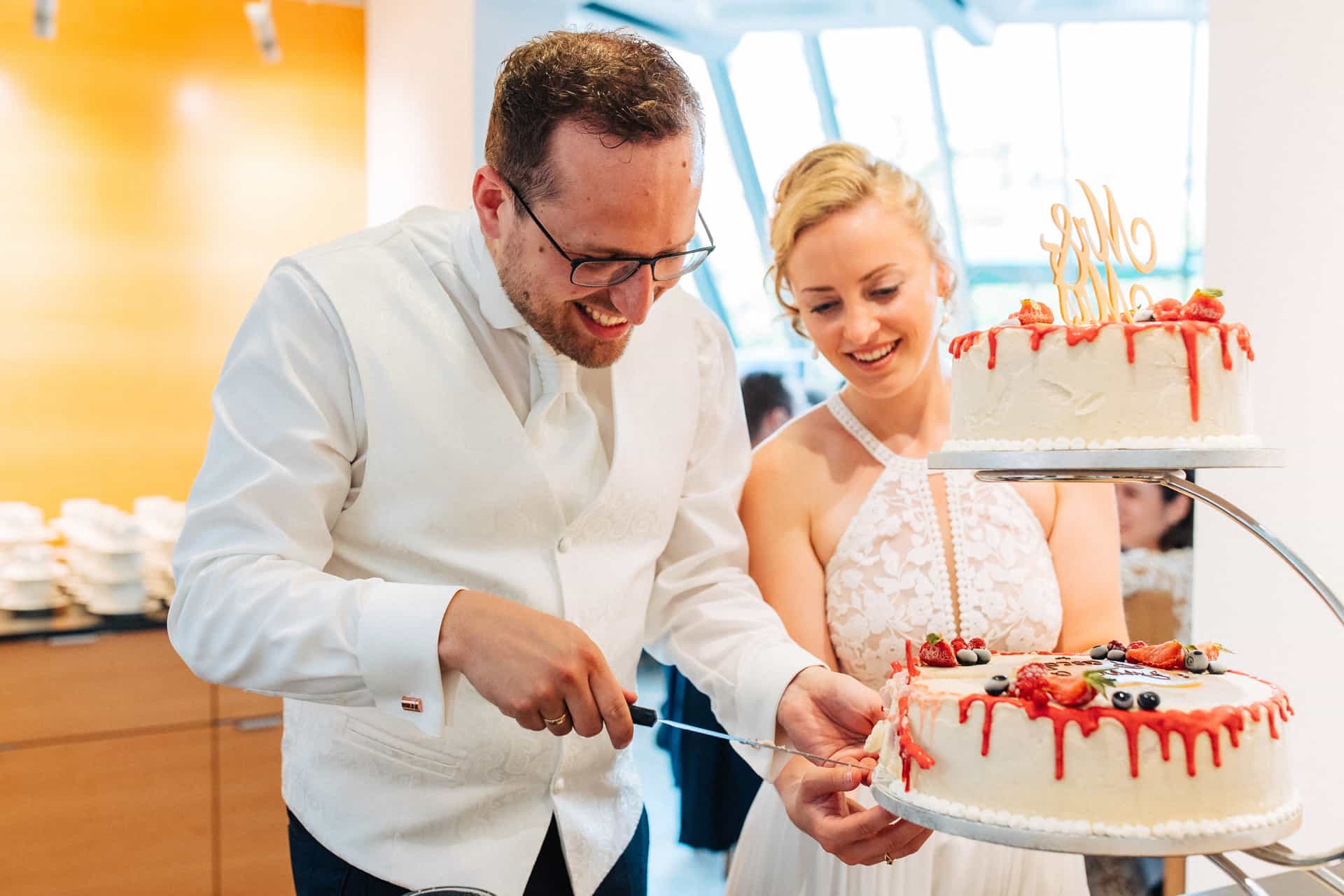 Braut und Bräutigam schneiden gemeinsam die Hochzeitstorte an.