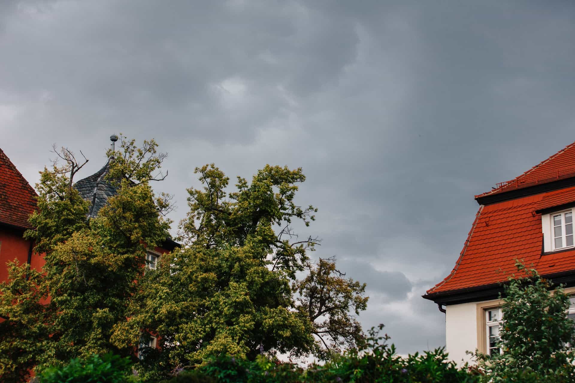 Dunkle Wolken über den Bäumen und Dächern