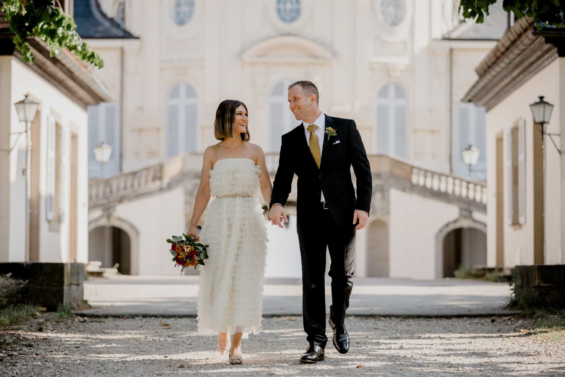 Brautpaar geht Hand in Hand über die Schlossterrasse