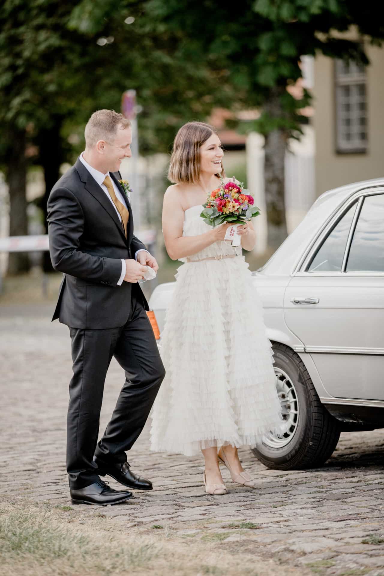 Bräutigam begleitet die Braut am Hochzeitswagen