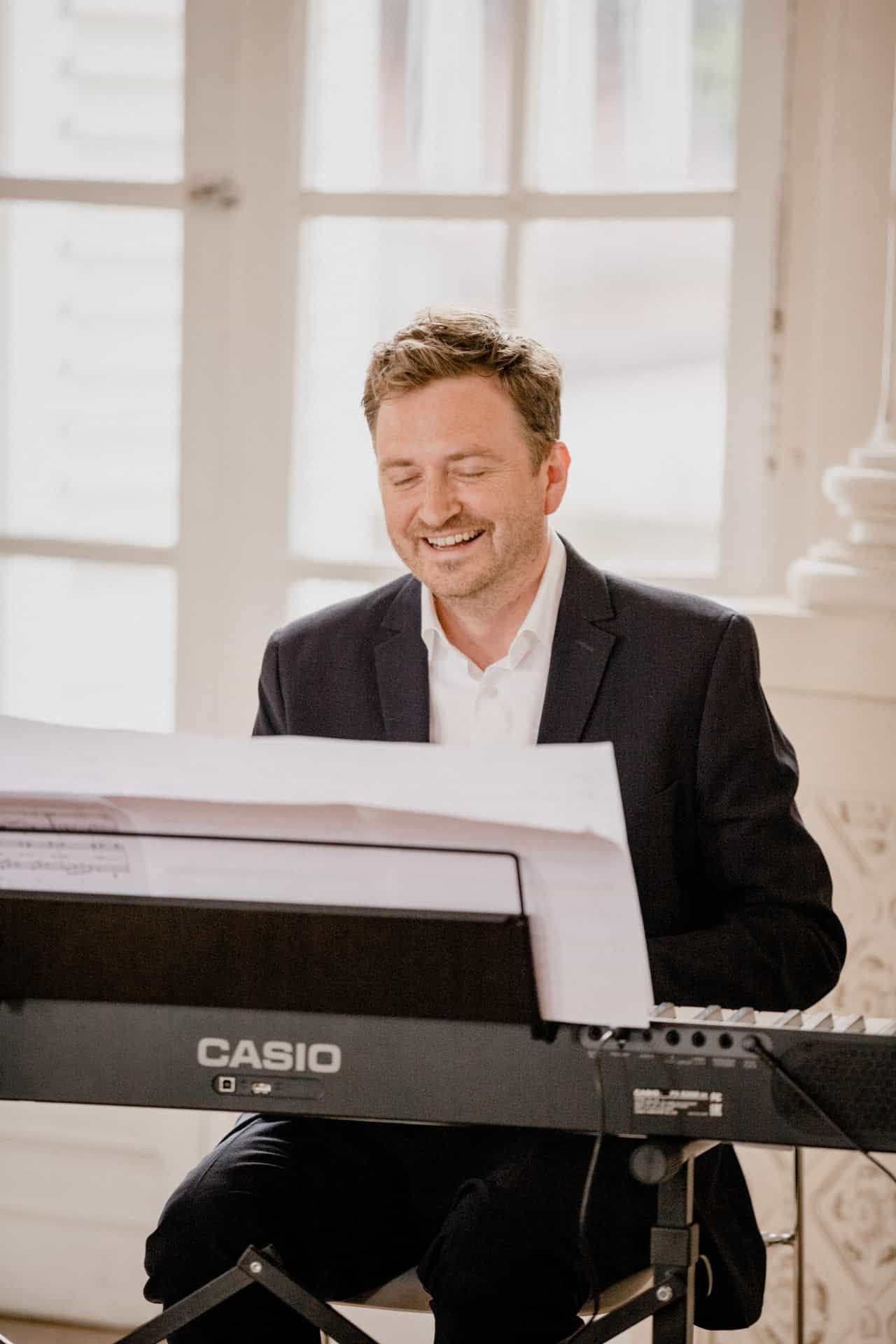 Lächelnder Musiker am Keyboard im Schlosssaal