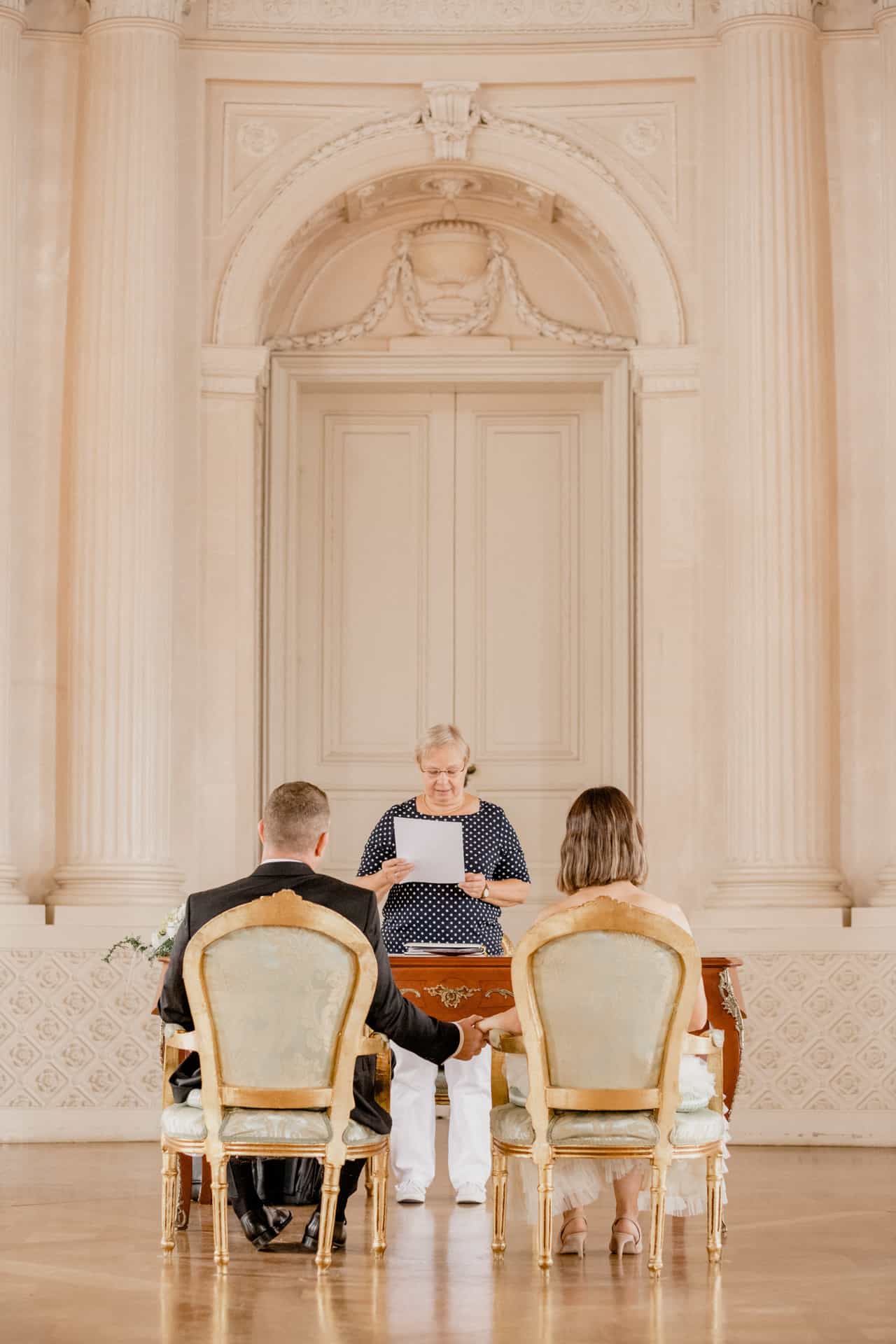 Brautpaar sitzt vor der Standesbeamtin im Schlosssaal