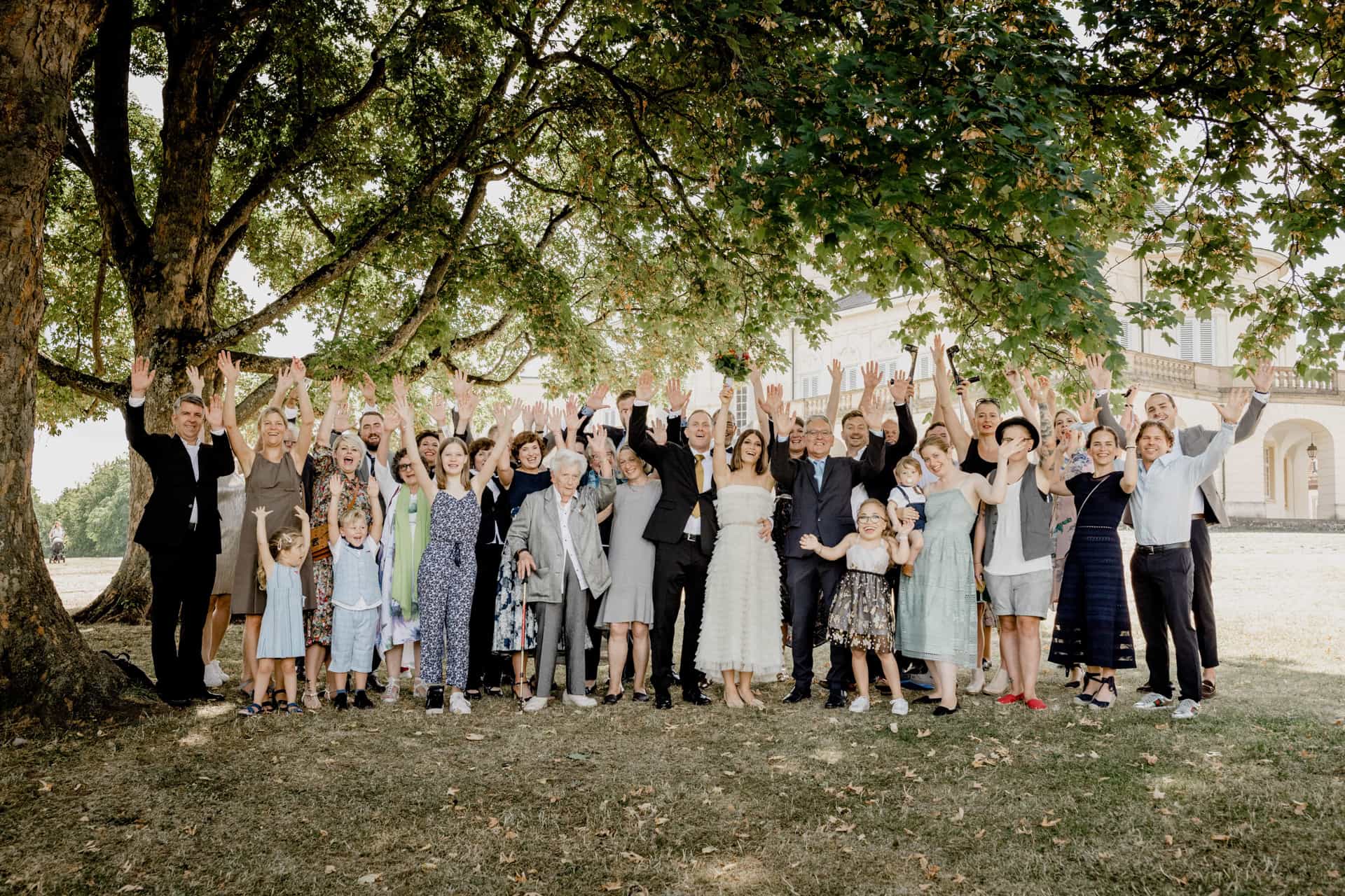 Gruppenfoto der Hochzeitsgesellschaft unter einem großen Baum