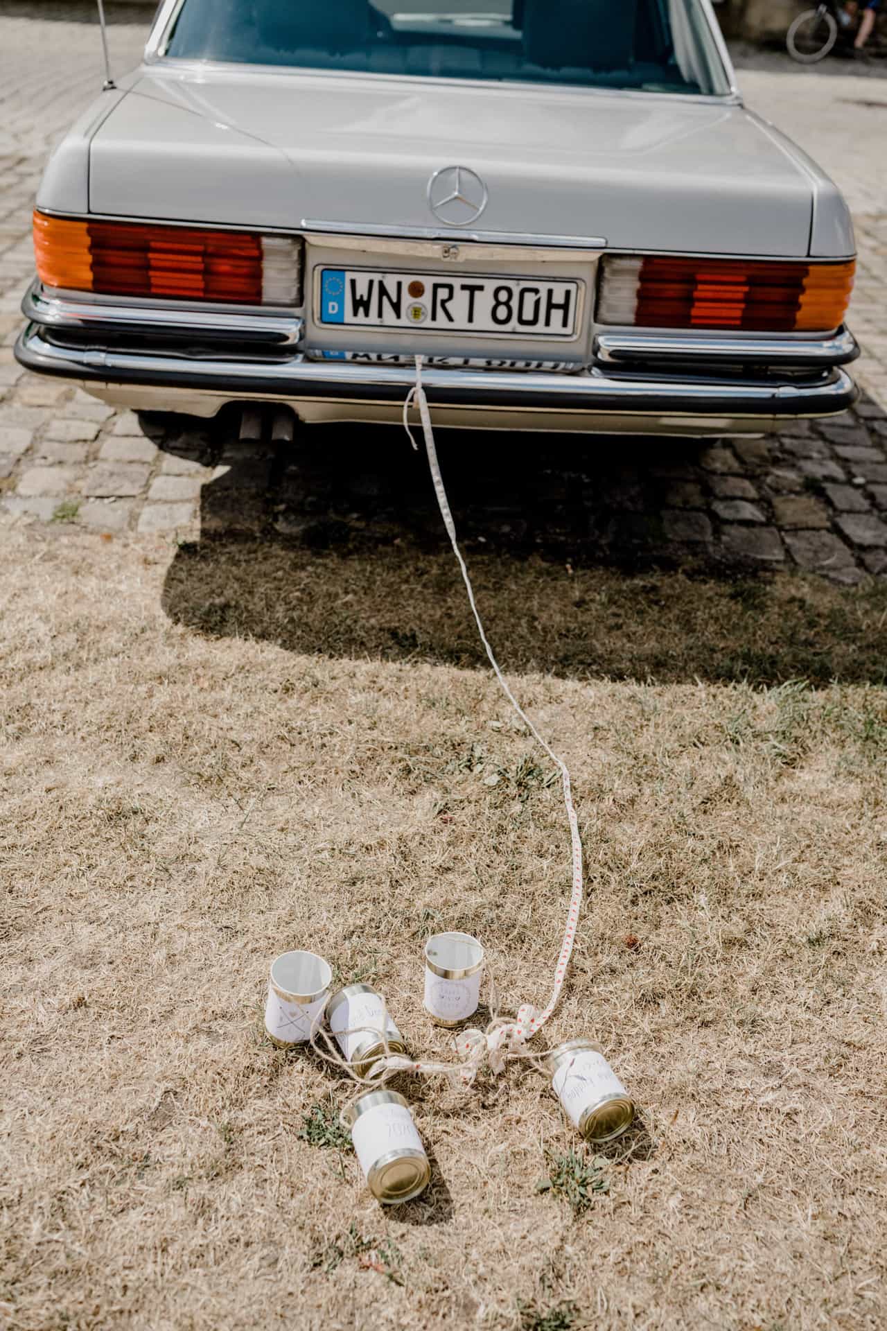 Blechdosen hängen als Hochzeitsschmuck am Heck des Oldtimers
