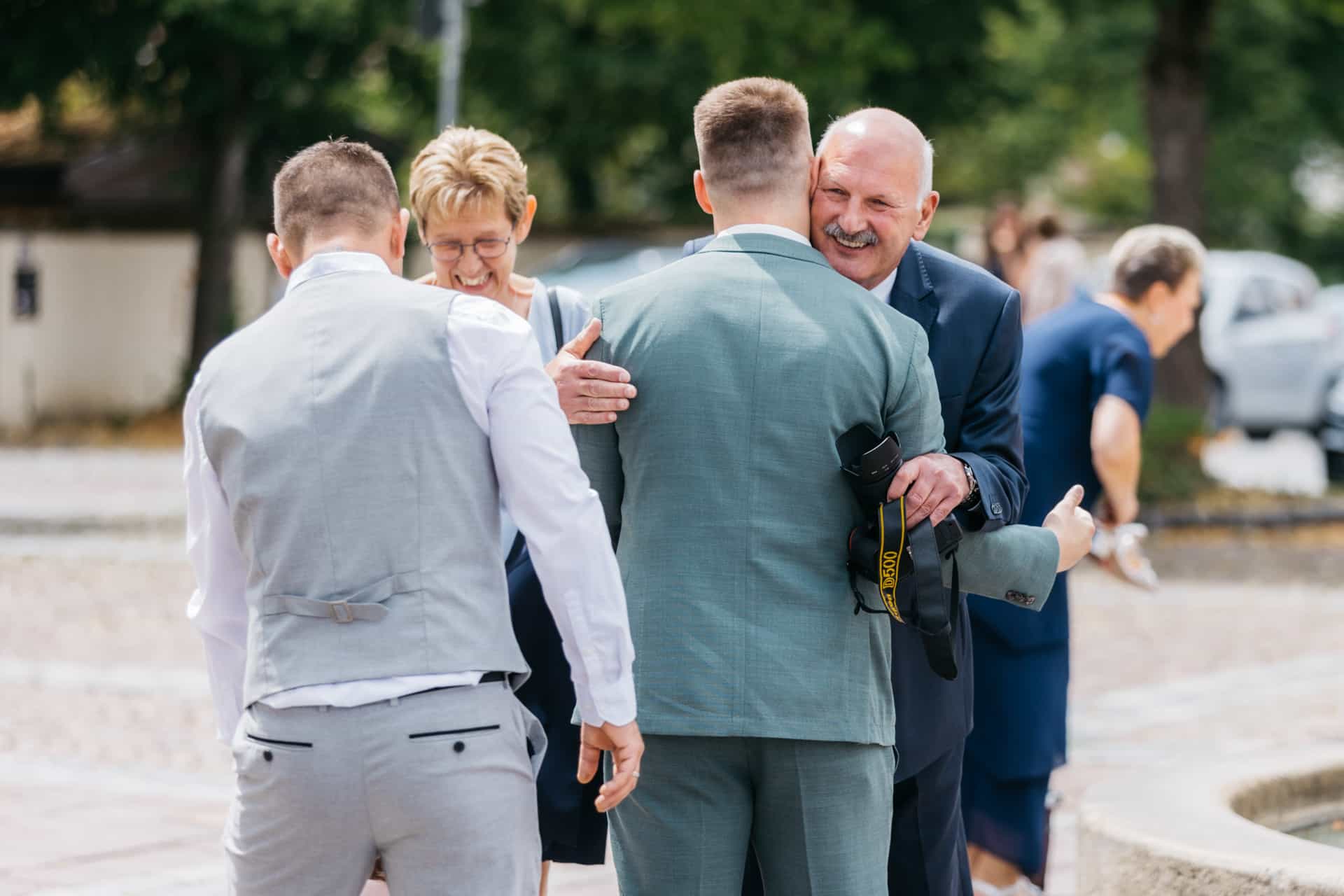 Bräutigam steht mit Gästen vor der Kirche