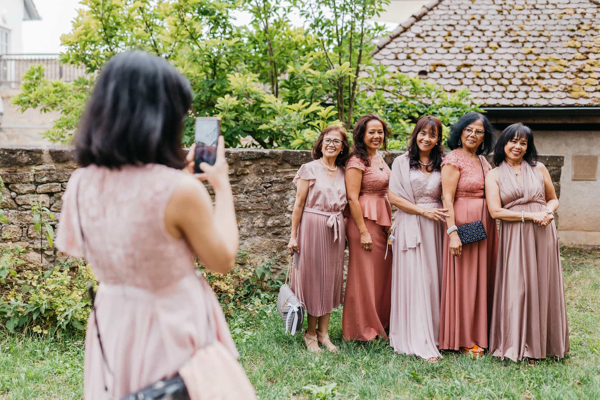 Eine Gästin fotografiert eine Gruppe in rosa Kleidern