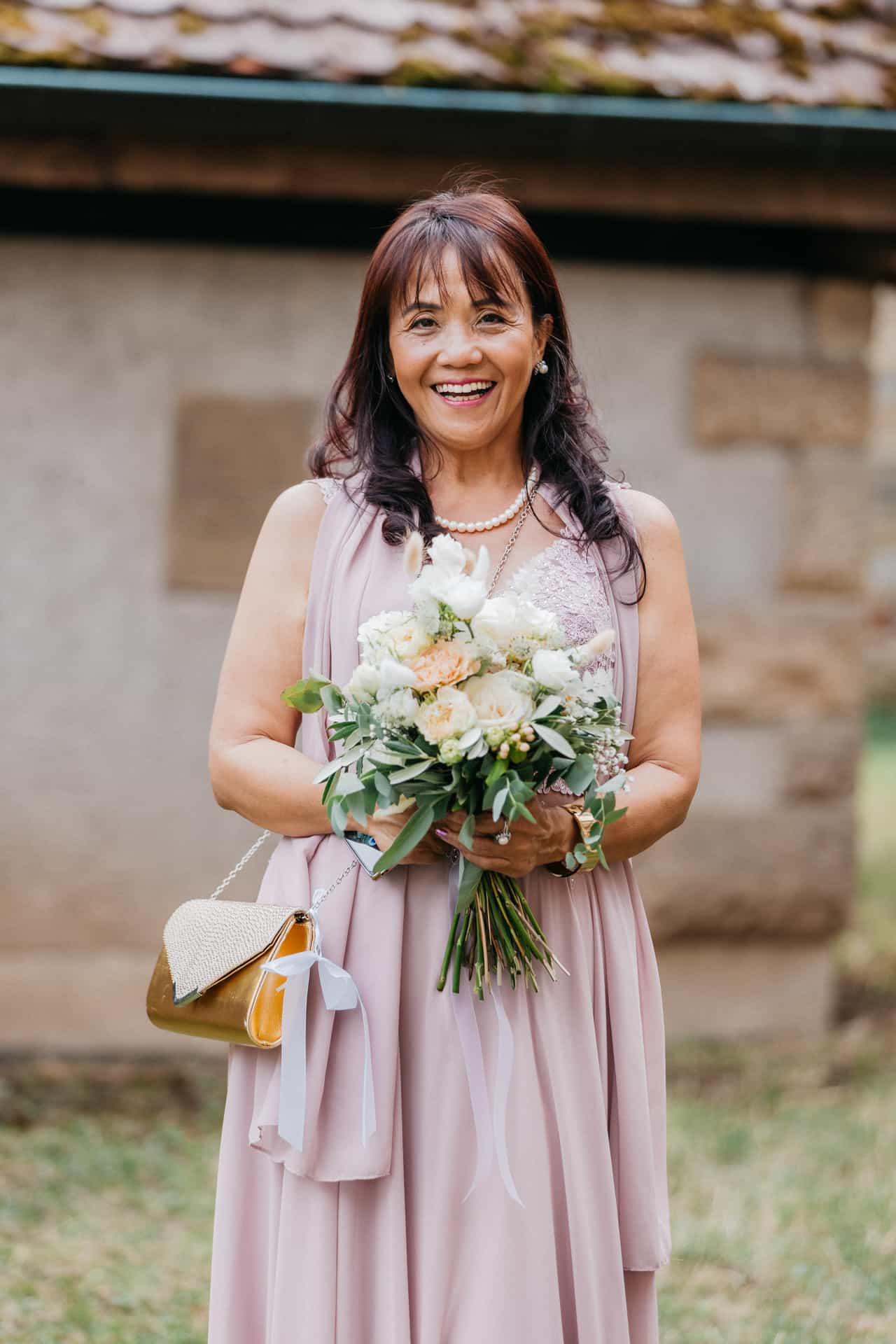 Hochzeitsgast im rosa Kleid mit Blumenstrauß