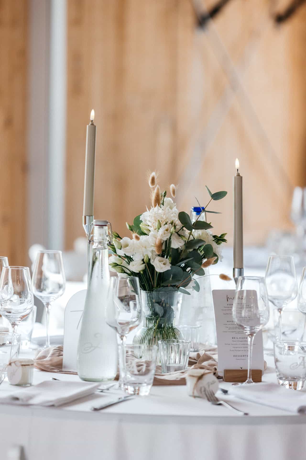 Weiße Blumen und Kerzen auf einer Hochzeitstafel