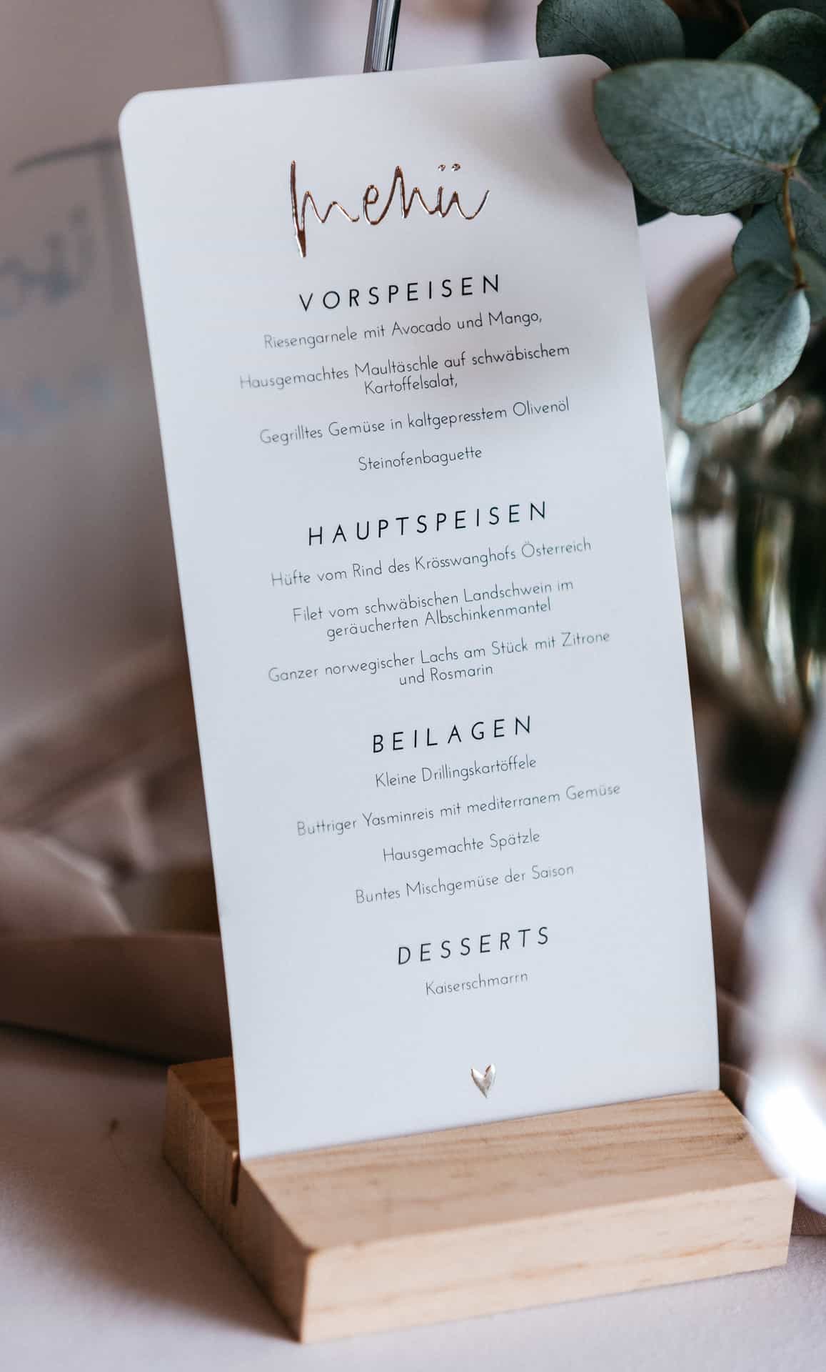 Eine gedruckte Karte in einem Holzhalter auf der Hochzeitstafel.