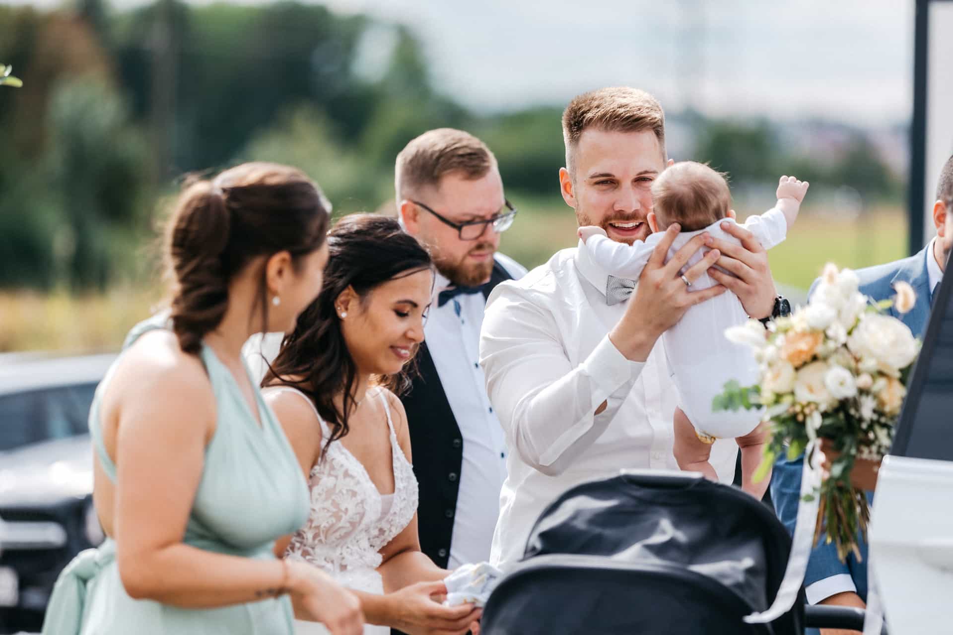 Gäste begrüßen sich neben einem Kinderwagen