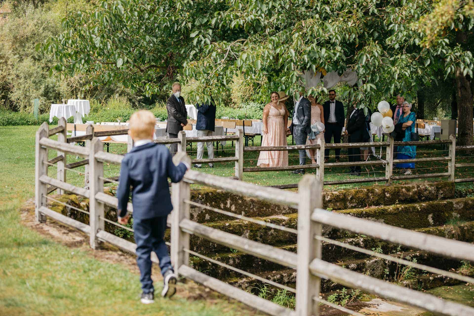 Ein Hochzeitsgast geht über den Holzsteg zur Gartenanlage.