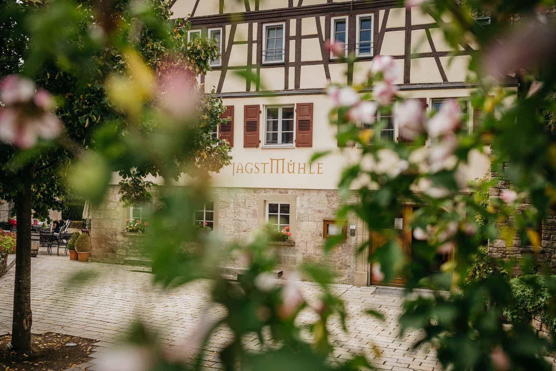 Fachwerkfassade der Jagstmühle hinter blühenden Zweigen
