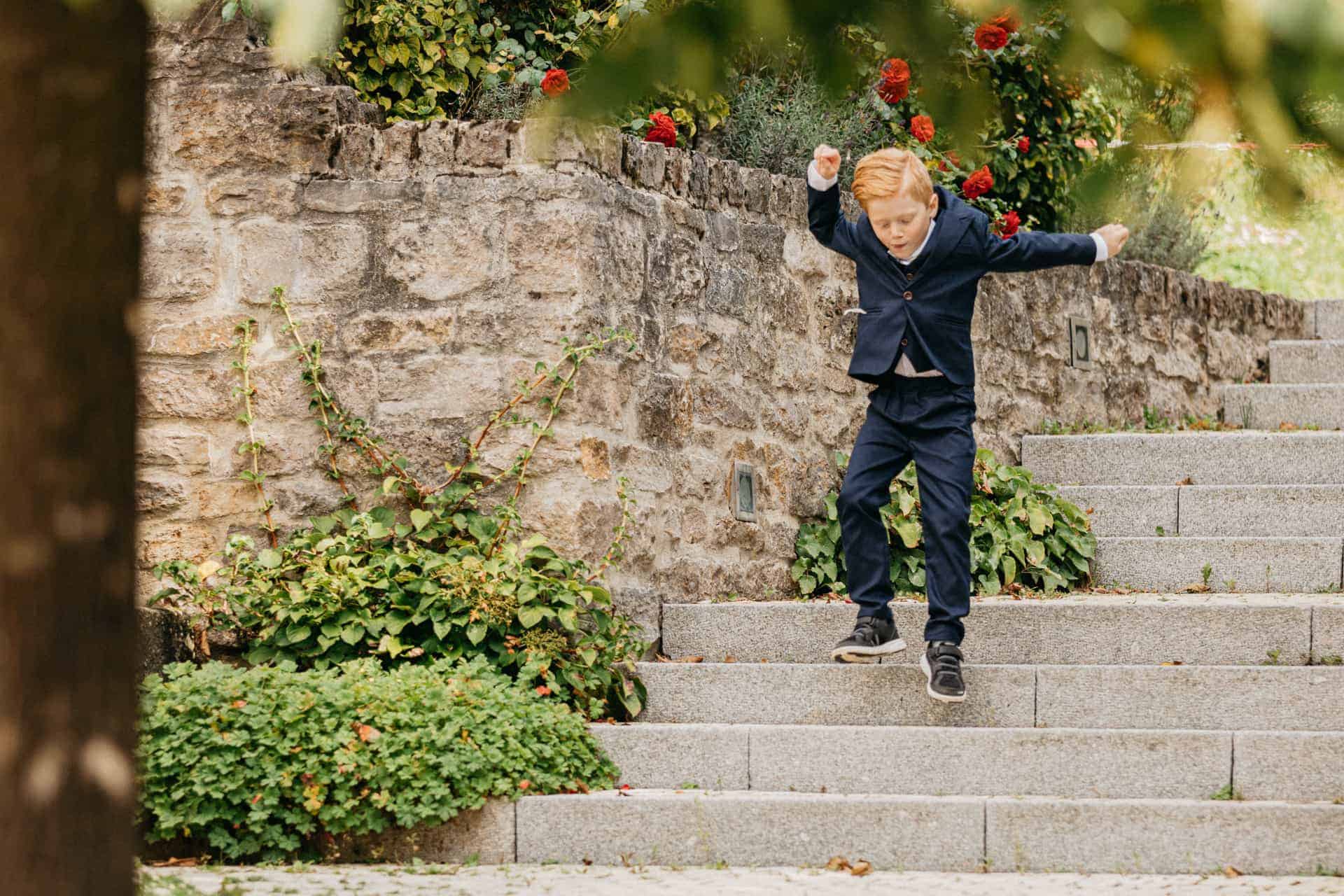 Ein Hochzeitsgast breitet auf einer Steintreppe die Arme aus.