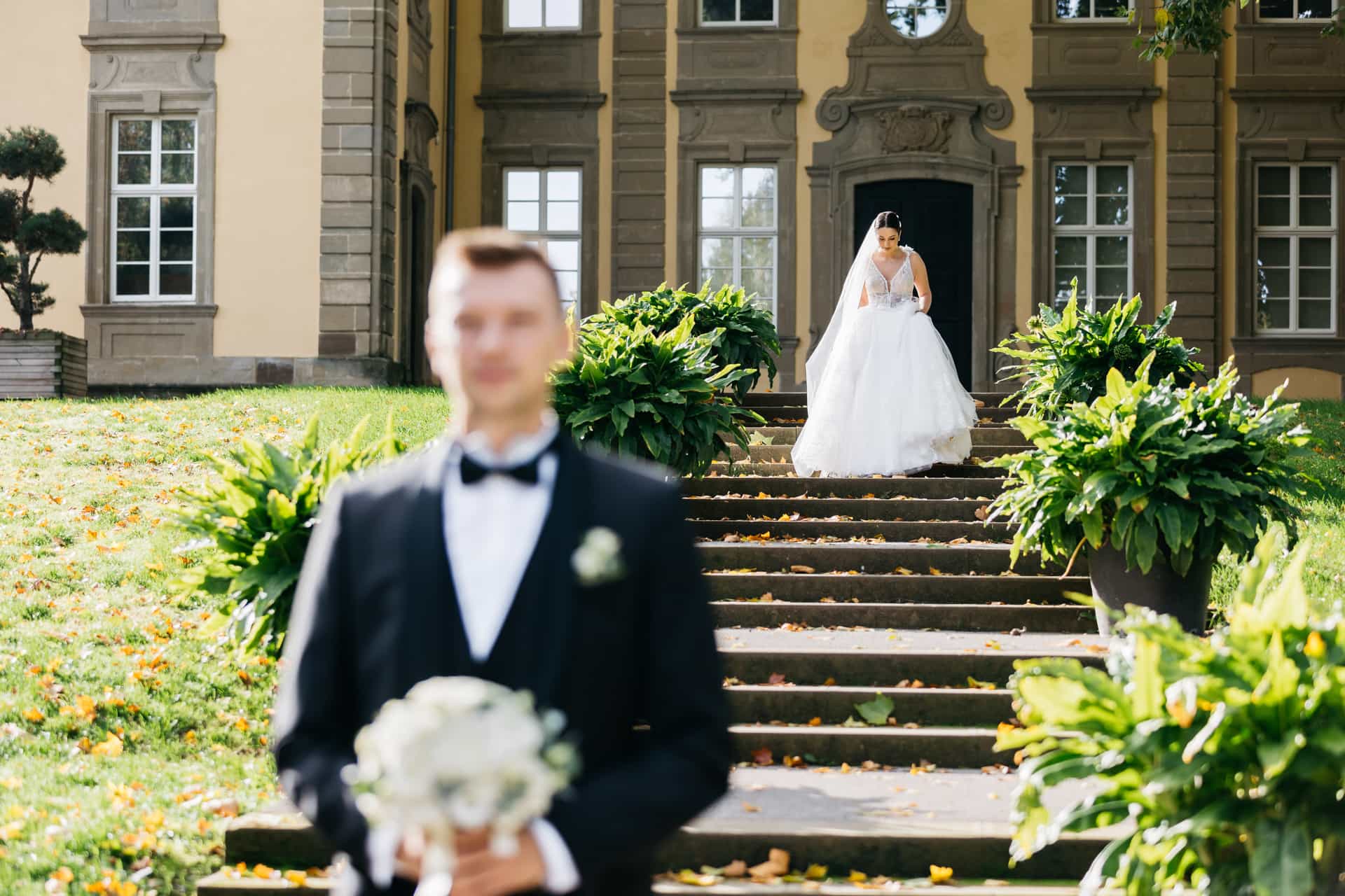 Adam wartet mit dem Brautstrauß auf der Treppe im Hofgarten Öhringen; Mara steht hinter ihm.