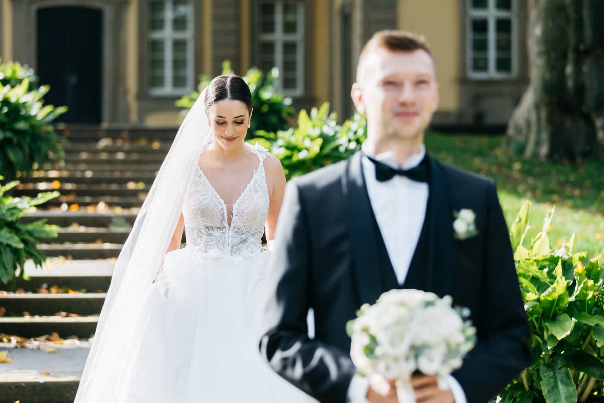 Braut nähert sich dem wartenden Bräutigam im Park