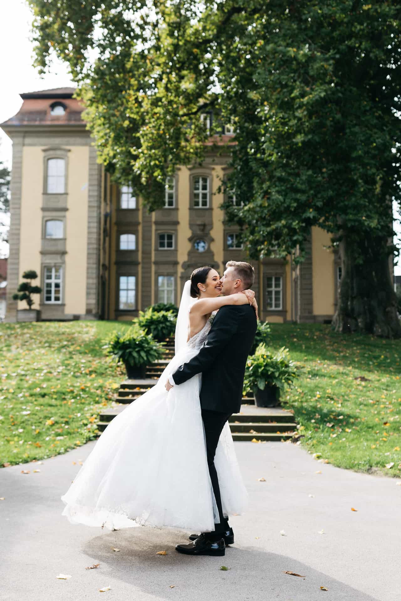 Adam hebt Mara im Hofgarten Öhringen lachend in die Arme.