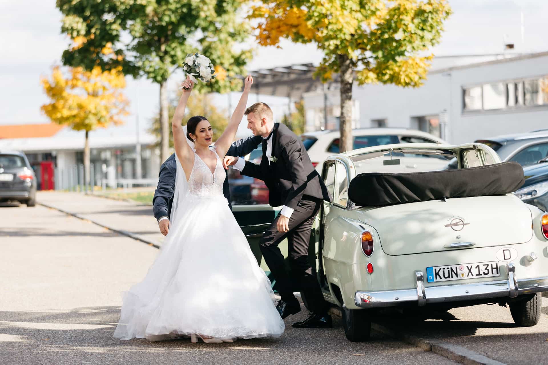 Mara steigt neben Adam aus dem Oldtimer.