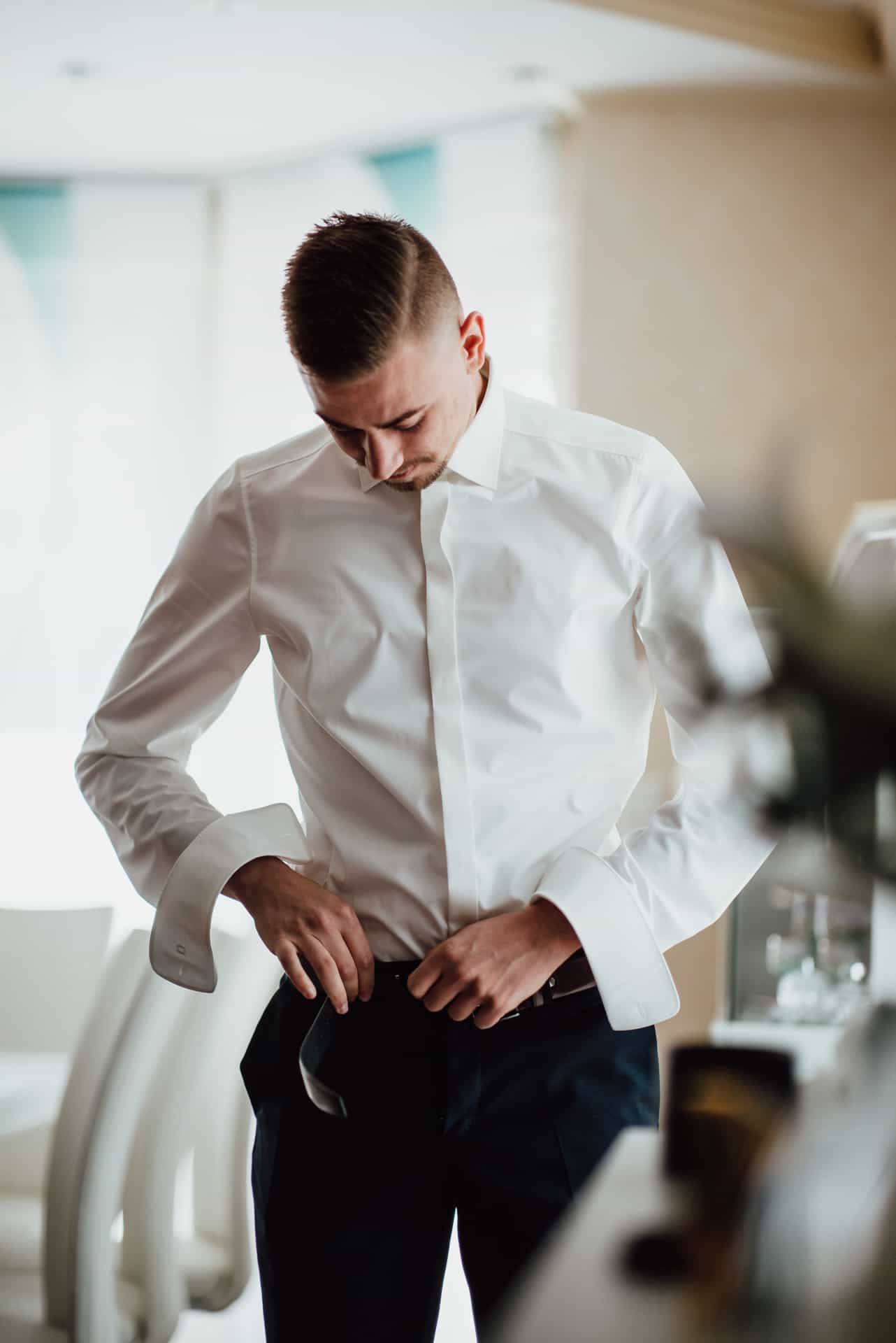 Bräutigam schließt beim Anziehen seinen Gürtel