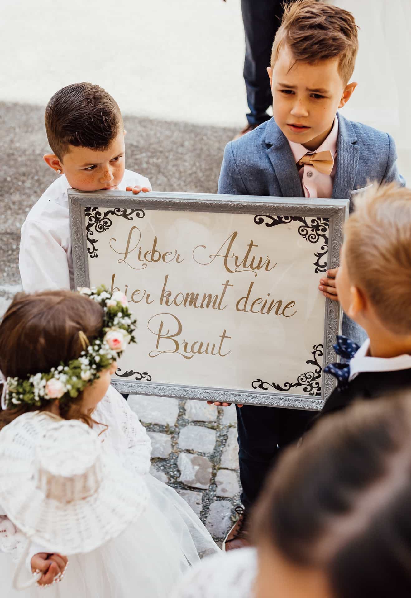 Zwei Kinder halten ein Schild zum Einzug der Braut