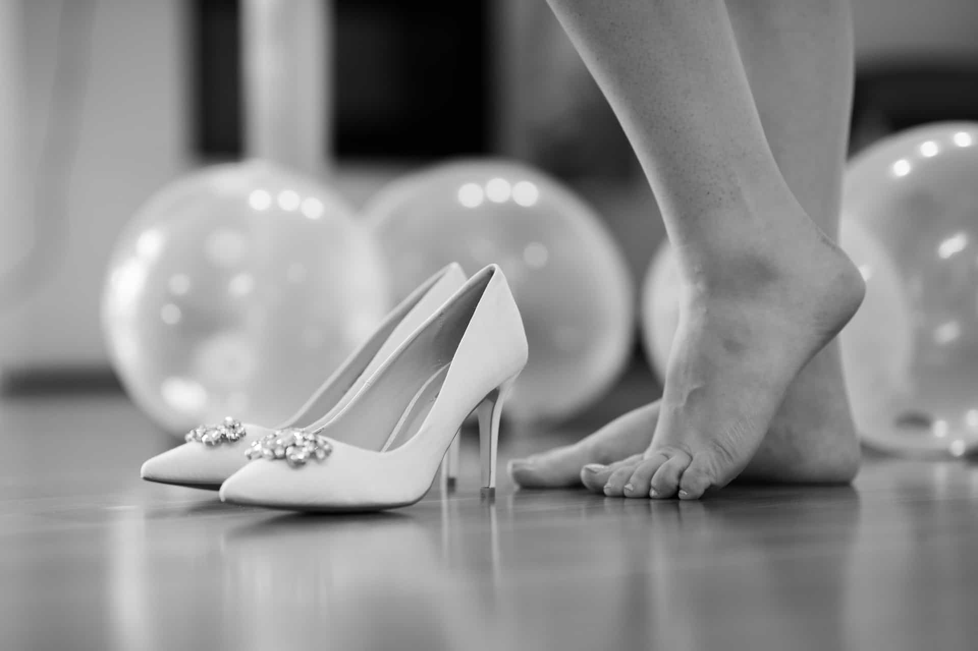 Weiße Brautschuhe vor Luftballons in Schwarz-Weiß