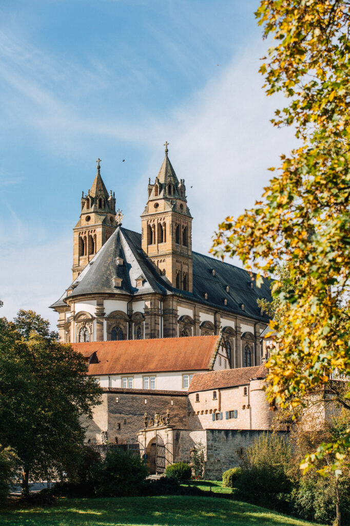 Die Türme der Comburg über herbstlichen Bäumen in Schwäbisch Hall.